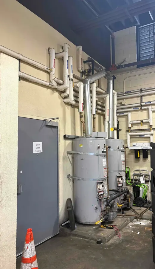 Commercial water heaters and piping installed against an exterior wall