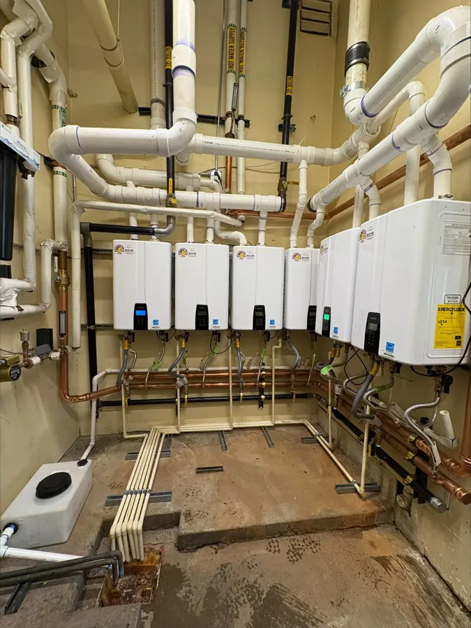 A row of tankless water heaters with new gas and water piping